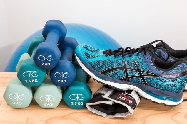 Apartments in The Heights Houston A pair of Asics shoes and a pair of dumbbells are arranged on a wooden table in a Fitness Center.